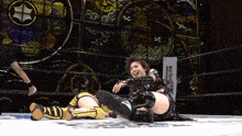 two women are wrestling in a ring with a stained glass background