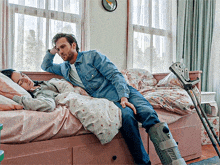 a man sits on a bed next to a woman with a broken leg