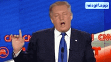 a man in a suit and tie is giving a middle finger sign