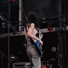 a woman playing a blue bass guitar on a stage