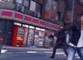 two people are walking down a street in front of a convenience store .