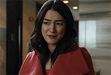 a woman wearing a red coat is making a sad face