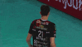 a man holding a volleyball in front of a scoreboard that says pga on it