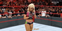 a woman is standing in a wrestling ring and talking to the crowd .