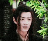 a young man with long black hair has a pendant on his head