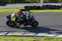 a person riding a motorcycle on a track with a helmet that has the word shark on it