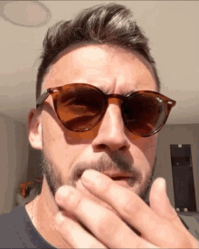 a man wearing sunglasses has his hand on his chin