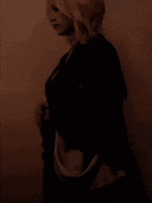 a woman in a black jacket and white shirt is standing in a dark room