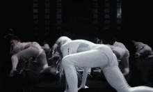 a group of dancers are dancing in a dark room and one of them has white hair
