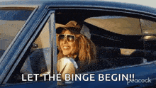 a woman is sitting in a car with the words `` let the binge begin '' written on the window .