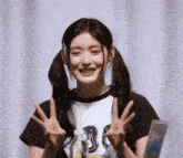 a girl with pigtails is smiling and making a peace sign with her hands