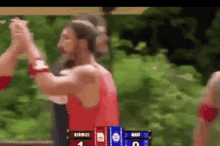a man in a red shirt is giving another man a high five while standing in front of a scoreboard .