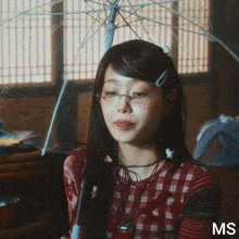 a woman holding an umbrella with the letters ms on the bottom right
