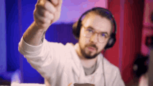 a man wearing headphones and glasses holds up his fist