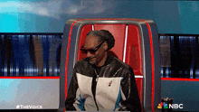 snoop dogg is sitting in a chair with a nbc logo behind him