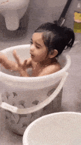 a little girl is taking a bath in a bucket with the word dao on the handle