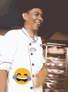 a man in a chef 's uniform is laughing with a smiley face on his chest