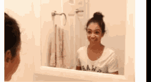 a woman in a raw shirt is smiling in front of a mirror