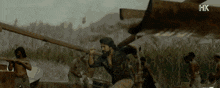 a man with a beard is holding a pole in a scene from a movie with hk written on the bottom
