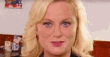 a close up of a woman 's face with blonde hair and blue eyes making a funny face .