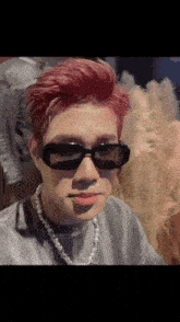 a man with red hair wearing sunglasses and a pearl necklace