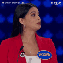 a woman wearing a red jacket and a blue badge that says victoria