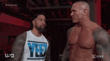 two wrestlers are standing next to each other and one of them is wearing a shirt that says yes