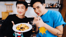 a man in a blue shirt holds a plate of food next to a man in a black shirt