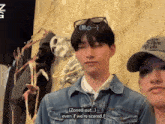 a man wearing a denim jacket and a hat that says be nice web