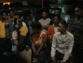 a group of young men are gathered in a room and one of them is wearing a jacket that says adidas on it