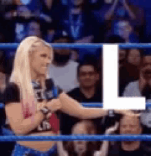a woman is standing in a wrestling ring with a microphone in her hand .
