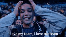a woman in a nike jacket holds her hands to her head and says i love my team