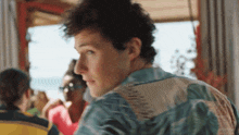 a man in a hawaiian shirt looks at the camera