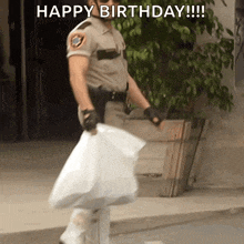 a man in a sheriff 's uniform is carrying a bag that says " happy birthday "
