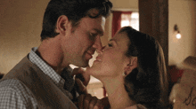 a man and a woman are kissing in front of a box that says so