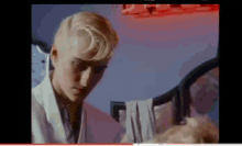 a woman with blonde hair and a white coat is looking down