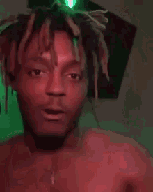 a shirtless man with dreadlocks is making a peace sign with his finger .