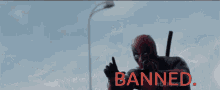 a man in a deadpool costume is standing in front of a sign that says banned