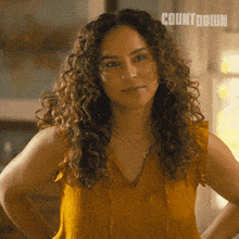 a woman with curly hair is standing with her hands on her hips in front of a countdown sign