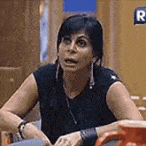 a woman in a black tank top is sitting at a table with a cup of coffee .