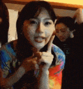 a woman is making a peace sign with her finger while standing in a room .
