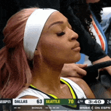 a female basketball player sits in the stands watching a game between dallas and seattle at 3:40