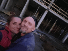 a man and woman pose for a picture in front of a building under construction