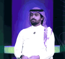 a man wearing a head scarf and a white shirt with a microphone on his neck