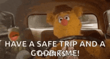 a muppet is driving a car with kermit the frog behind him .