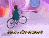 a woman is riding a bicycle with the words here she comes in the background