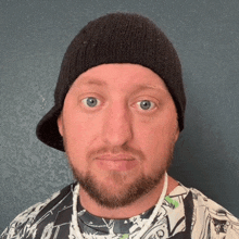a man with a beard wearing a black beanie and a shirt that says ' a ' on it