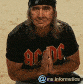 a man wearing a black shirt that says ac dc with his hands folded