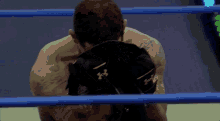 a man in a boxing ring is wearing a black under armour glove on his back
