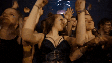 a group of people are dancing with their arms in the air and one of them is wearing a black corset